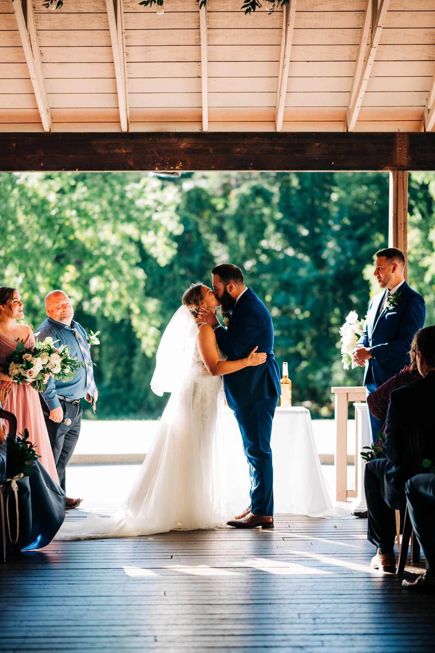 Bride and groom first kiss at wedding ceremony at Pine Knob Carriage House
