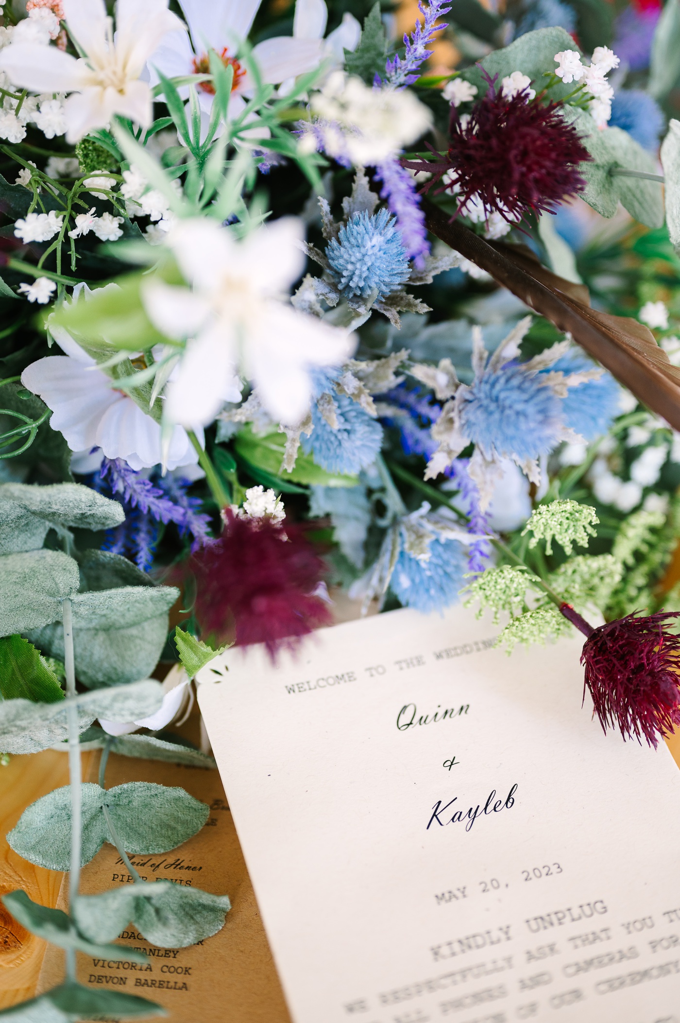 Close-up photo of a blue and purple wedding bouquet with a wedding ceremony program