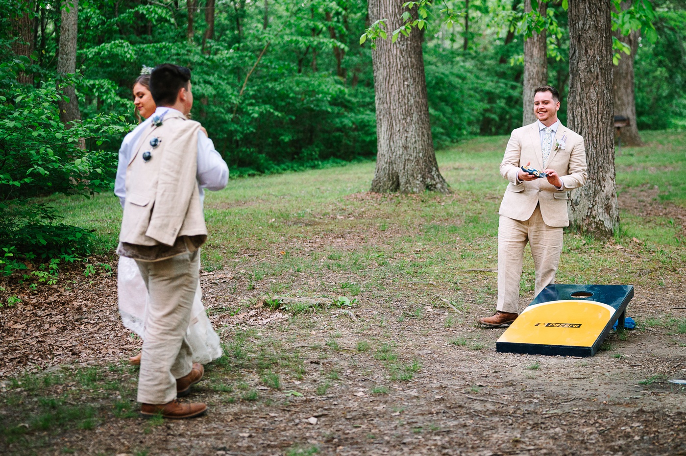 Groom playing cornhole at his outdoor wedding reception