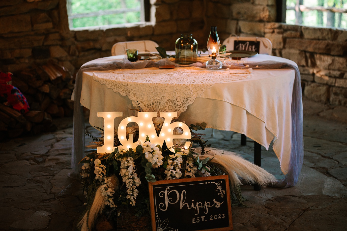 "Love" marquee sign in front of a rustic sweetheart table