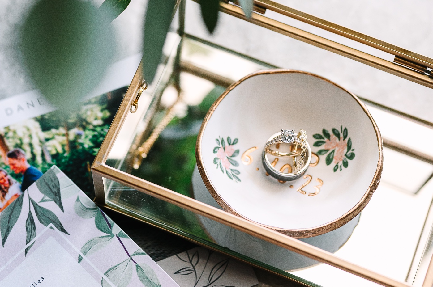 Flatlay with botanical wedding invitations and custom ring dish