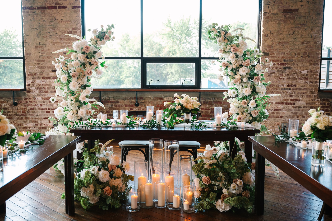 Sweetheart table with a white and blush floral crescent arch and candles