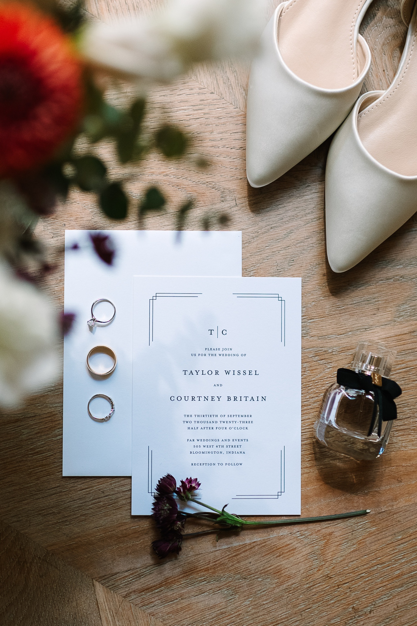 Flatlay with a black and white wedding invitation, white bridal shoes, and YSL perfume