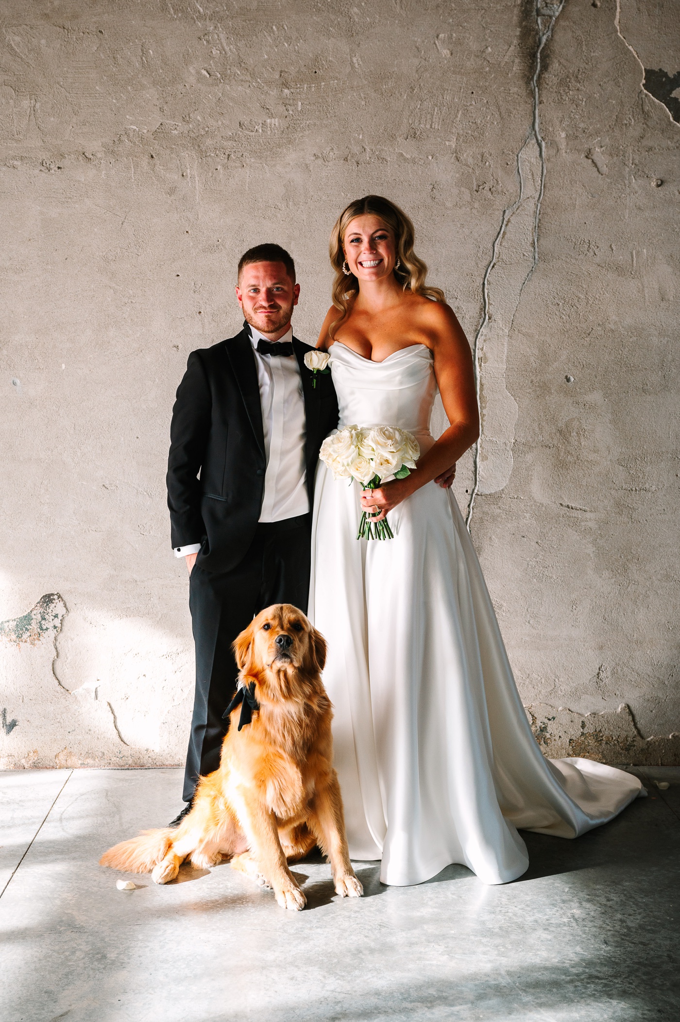 Bride and groom posing with their golden retriever at Ivory Foundry