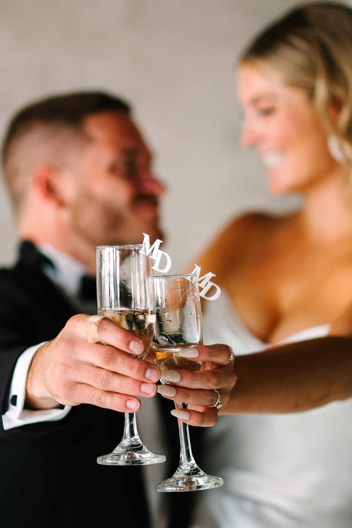 Bride and groom holding out custom initial champagne glasses