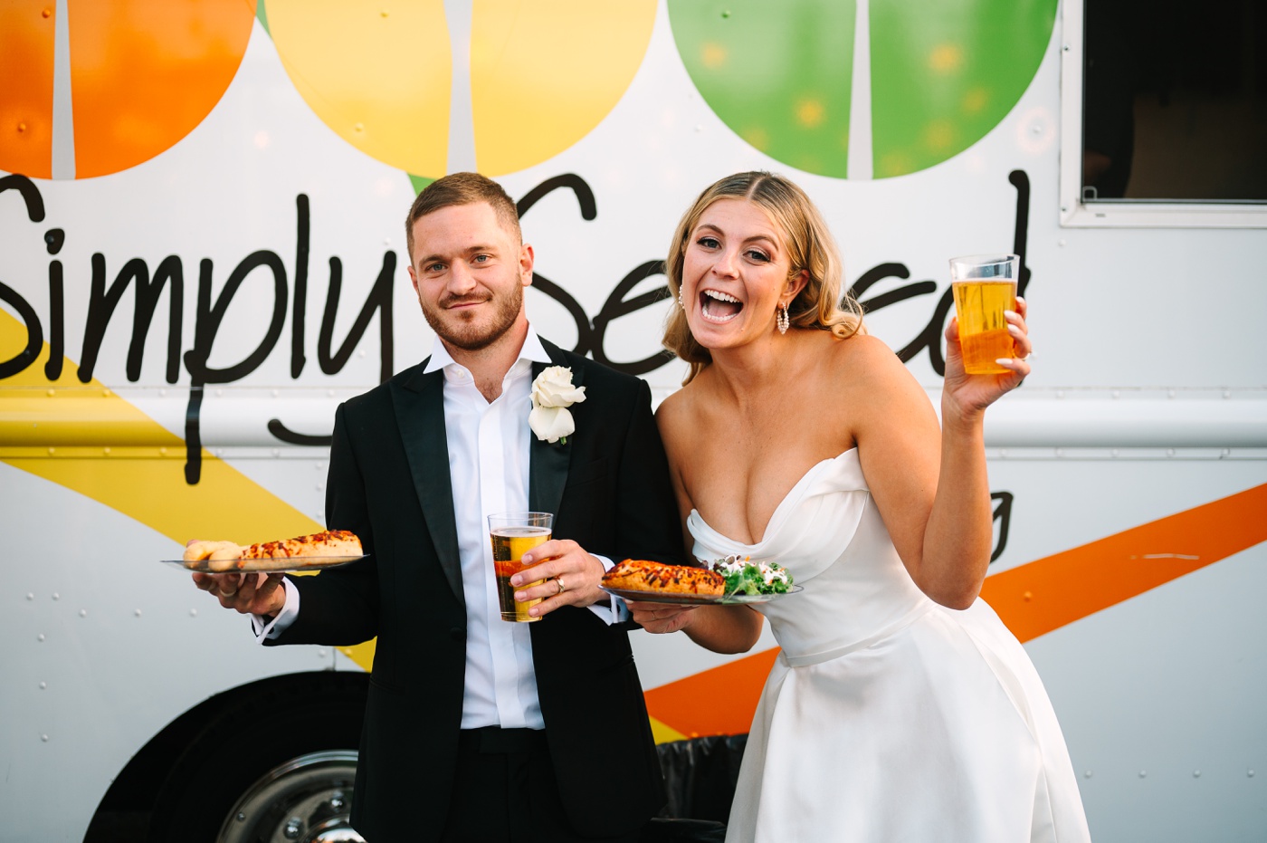 Bride and groom holding pizza and beer in front of the Simply Served Catering truck at their Indianapolis wedding
