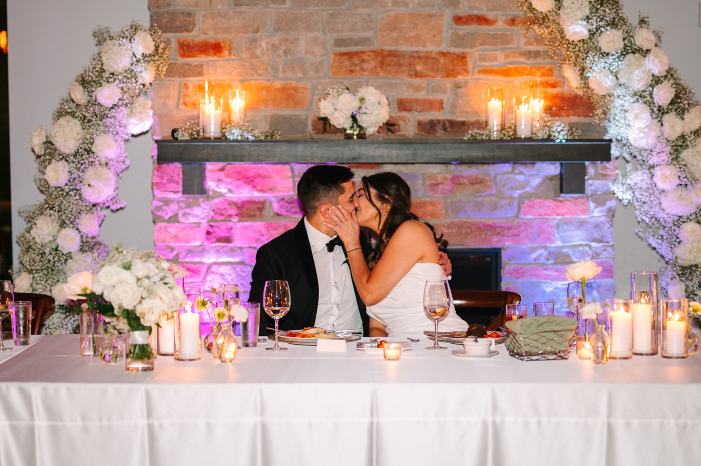 Bride and groom kissing in front of the fireplace at The Bluffs at Conner Prairie