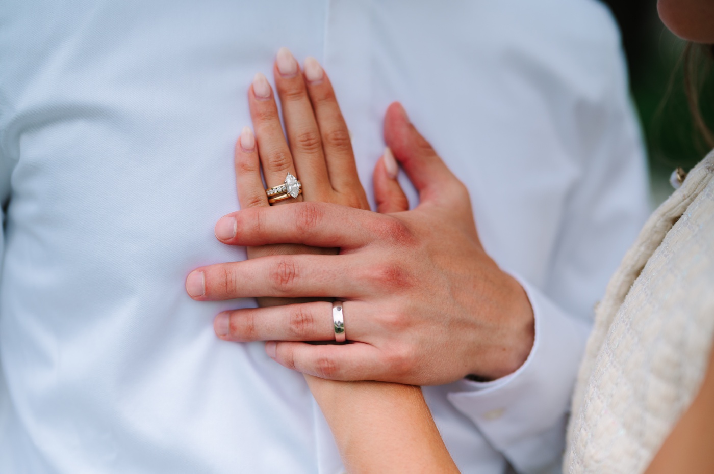 Bride's hand on groom's chest, wedding rings close-up